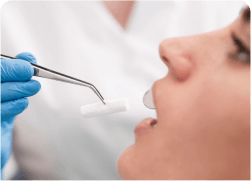 woman getting her teeth brushed by a dentist with a pair of blue gloves