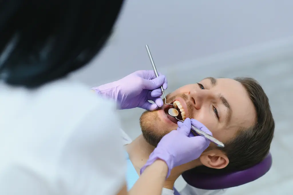 arafed man getting his teeth brushed by a dentist