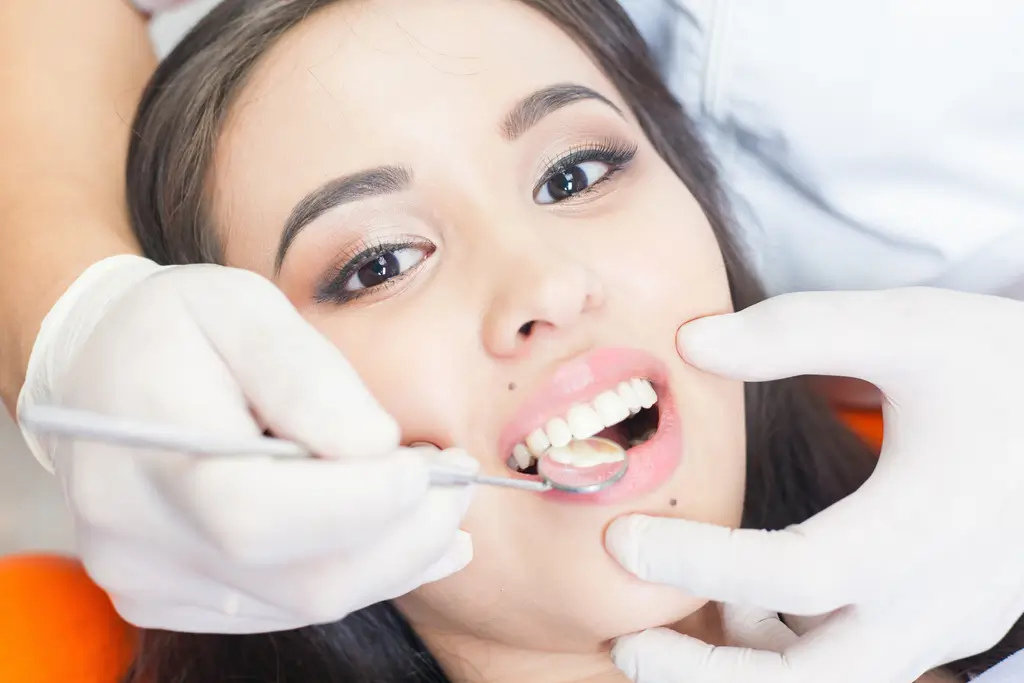 arafed woman getting her teeth brushed by a dentist